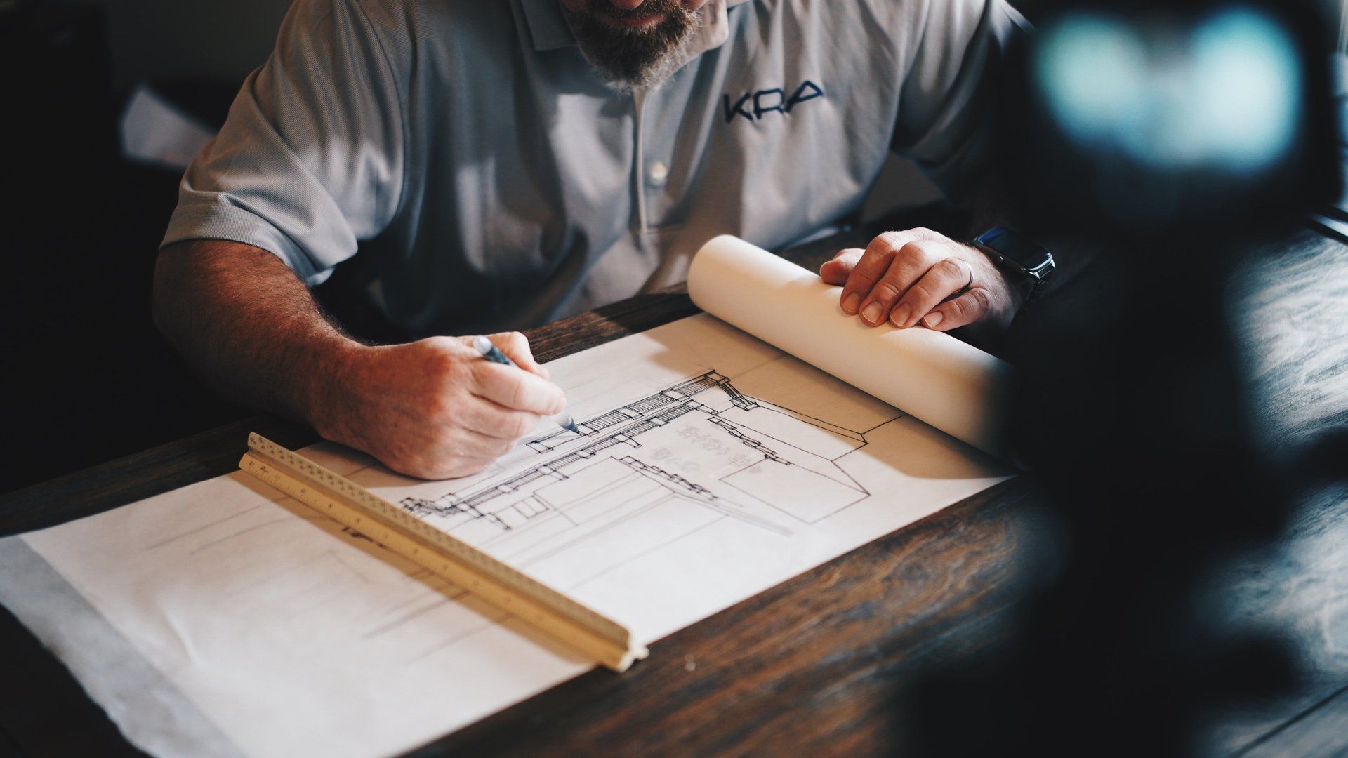 A picture of a man drawing a design on some paper.